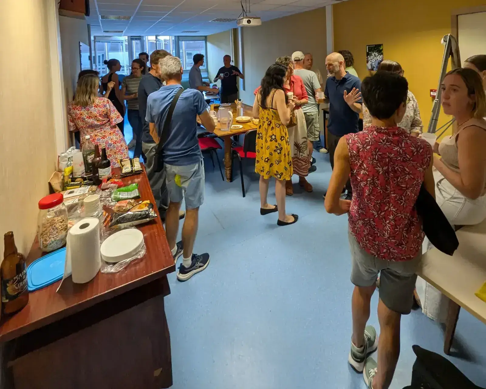 Une vingtaine de personnes debout, verre à la main, lors d'un apéro franco-anglais
