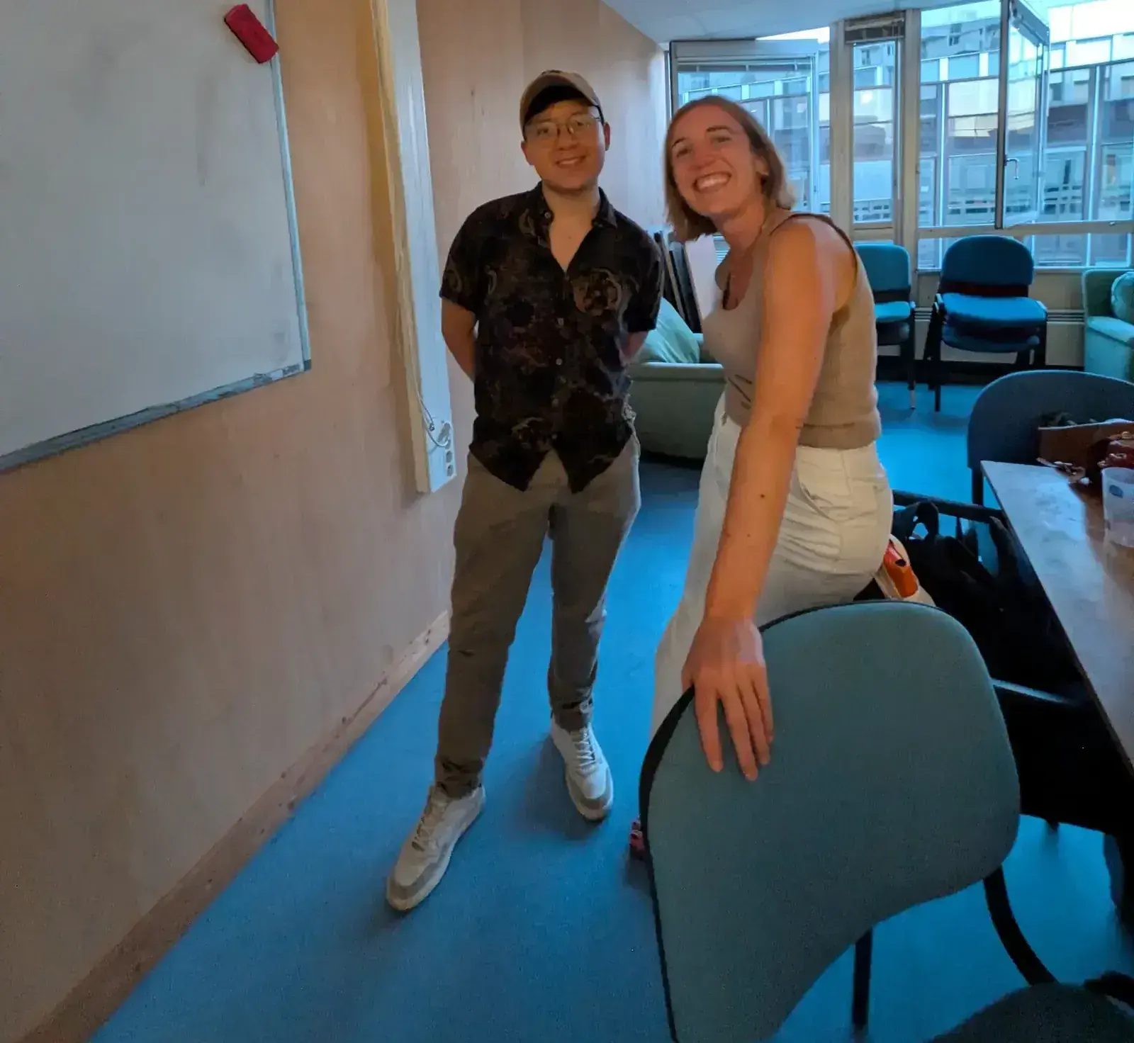 Deux apprenants souriants dans la salle de cours, tableau blanc derrière eux