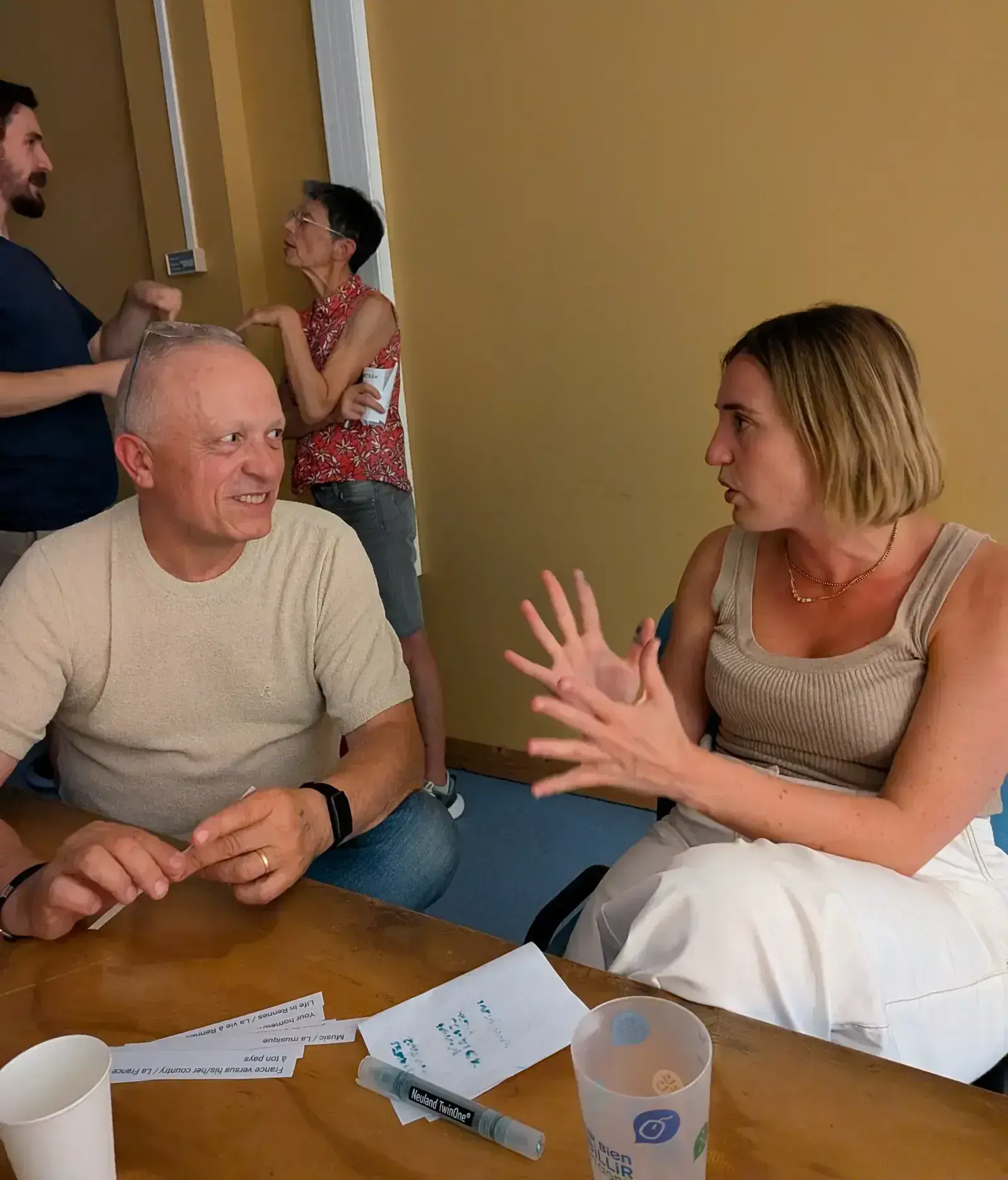 Deux participants en pleine conversation, cartes de sujets posées sur la table