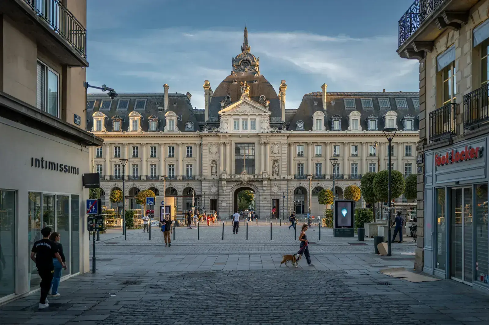 Le Palais du Commerce à Rennes en fin de journée, vu depuis une rue piétonne pavée du centre-ville