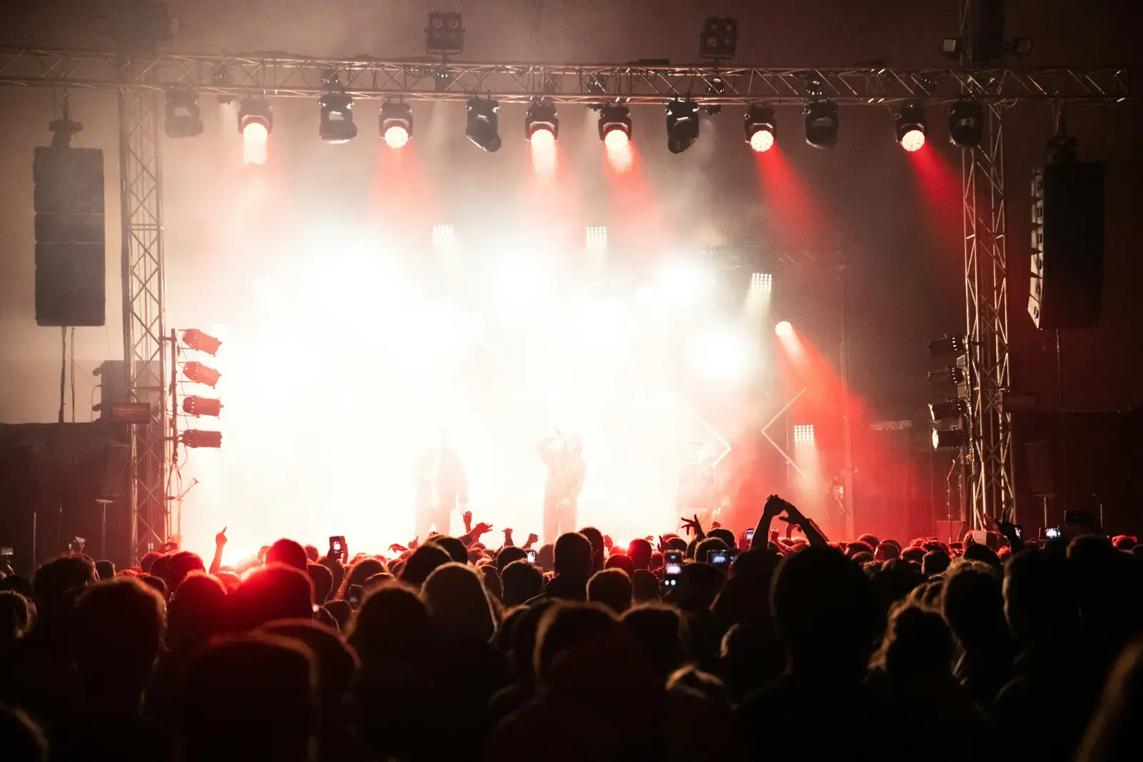 Foule devant une scène éclairée en rouge lors d'un concert en plein air, la nuit
